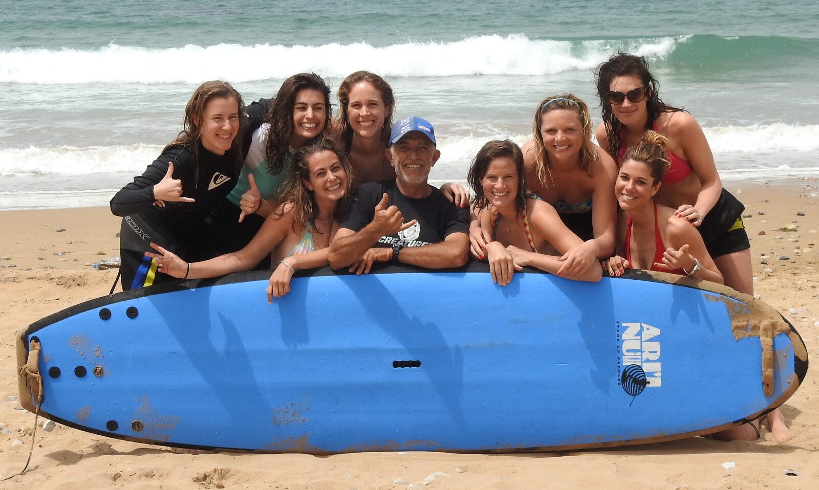 Group of women after a collective surf lesson in Agadir with their coach Hervé Pignoges and an ART NU SUP longboard on the beach.